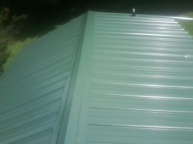 New green metal panels meeting at the ridge of a roof — Flat Roof Repair work by our crew in Atlantic